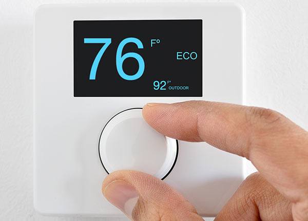 hand setting a thermostat to 76