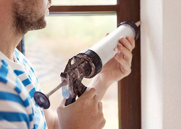 man caulking a window