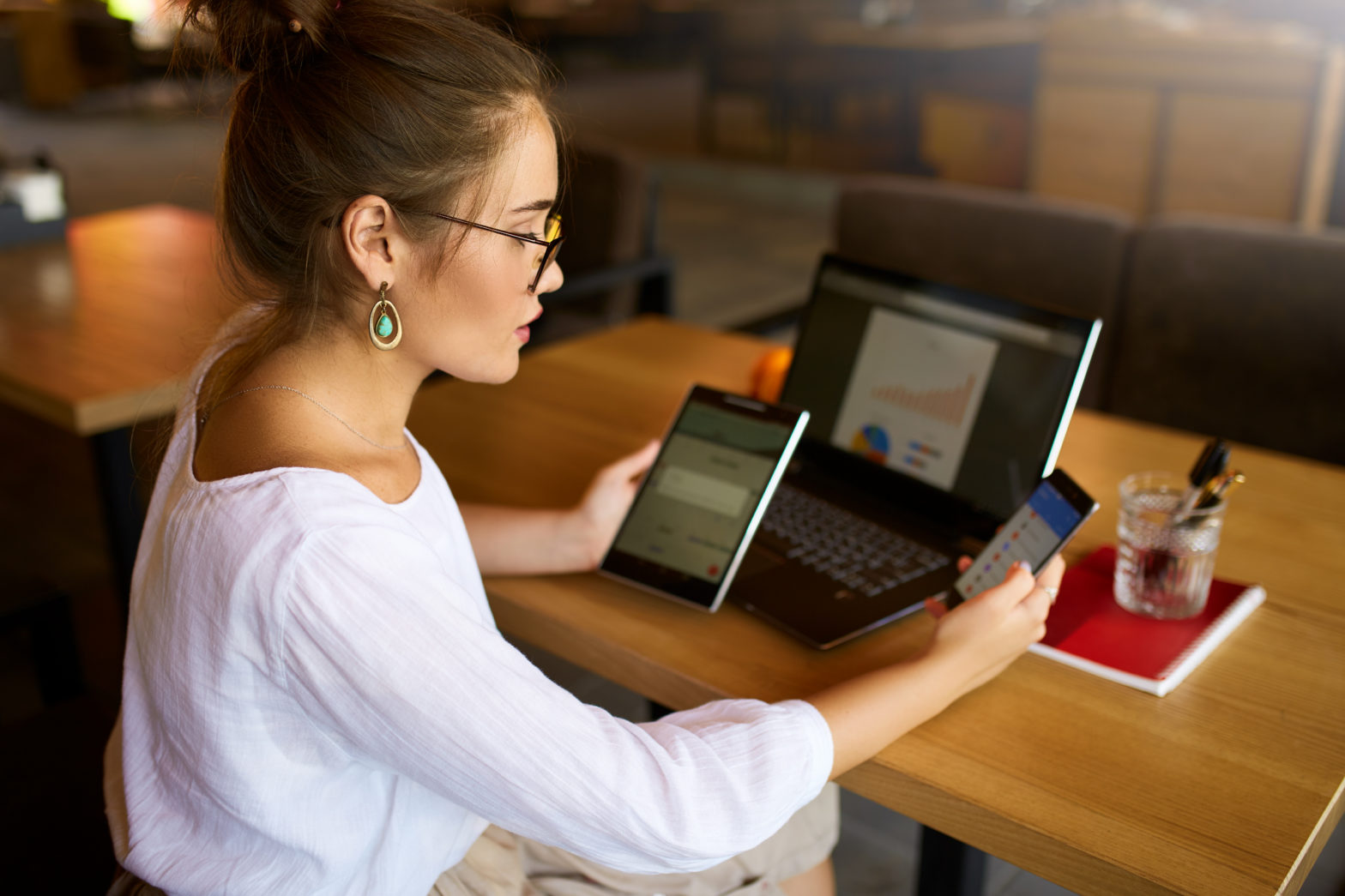 Woman at table with laptop, tablet, and phone