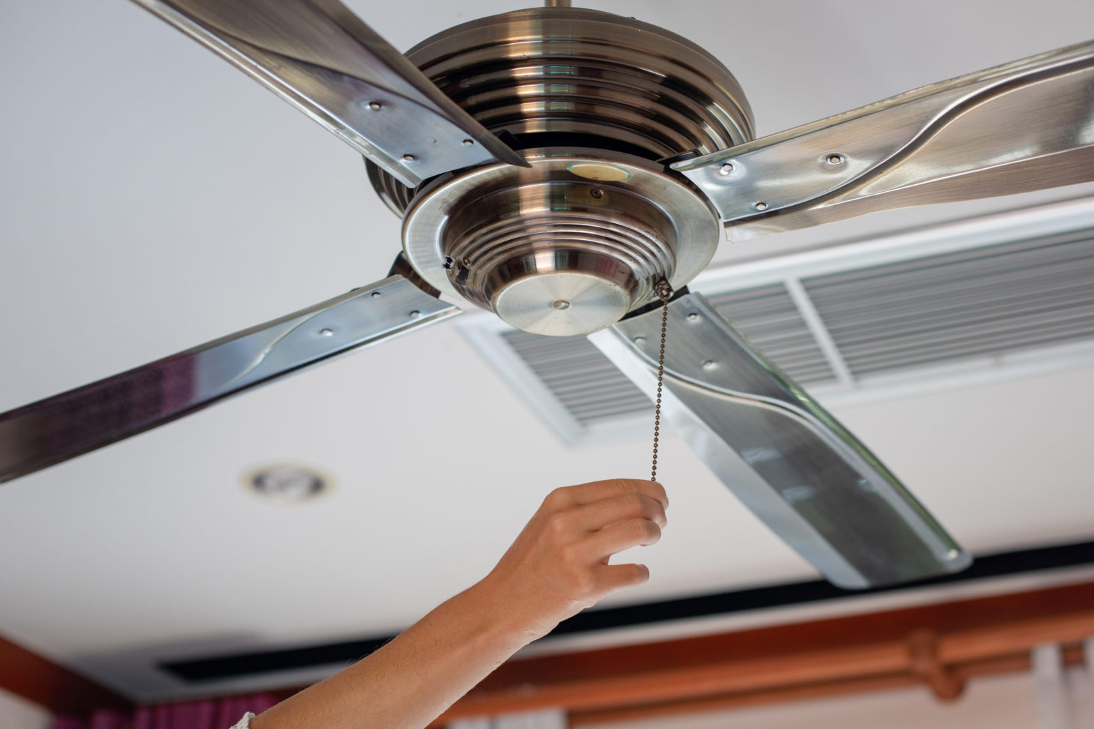 Person adjusting a ceiling fan