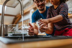 Adorable little girl helping her father to wash all dishes at home